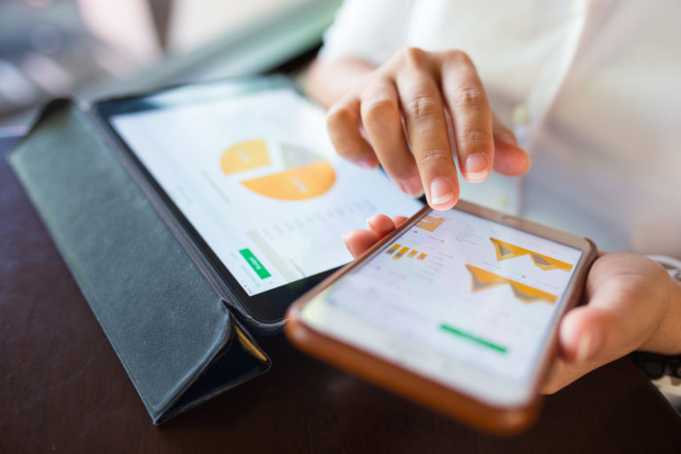 Businessperson checking data on smartphone and tablet